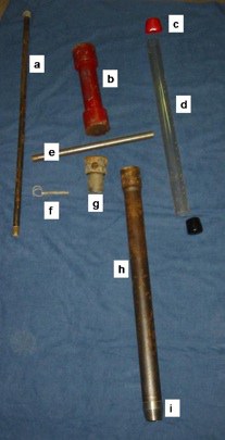 Equipment for acquiring soil core: a) slide hammer rod (screws into drive head), b) slide hammer, c) caps for retaining soil in the plastic liner tube, d) plastic liner tube, e) rod for removing core (slides through hole in drive head), f) pin to attach d
