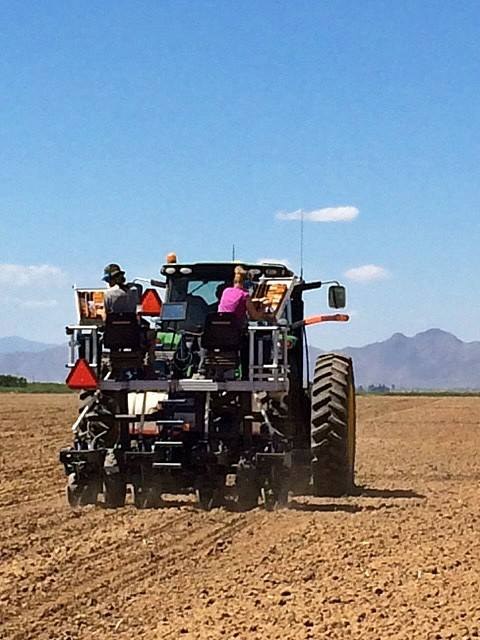Graduate students Jimmy Burridge and Hannah Schneider sitting on the precision planter during maize planting.